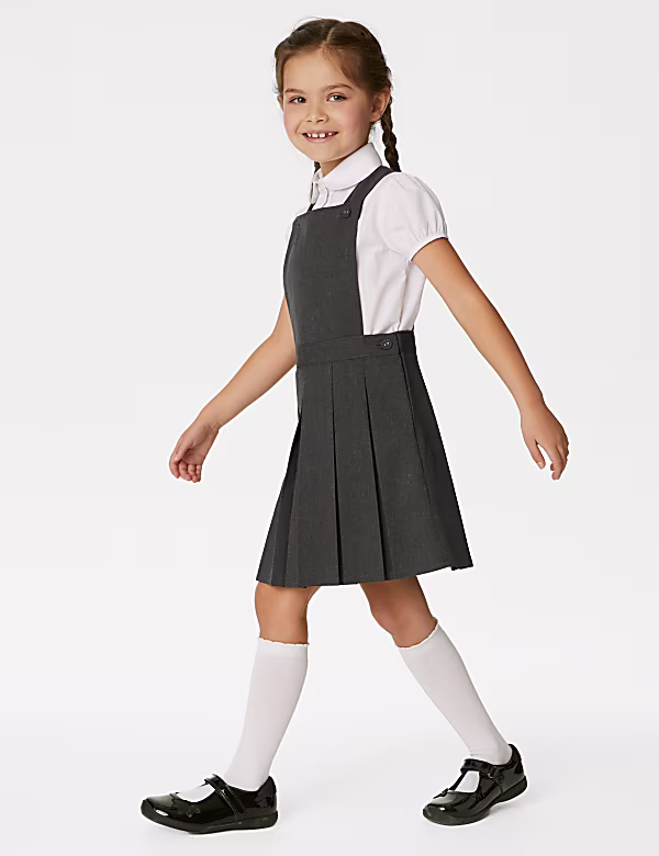 Grey pleated school dress with adjustable straps, paired with a white shirt, white socks, and black patent shoes.