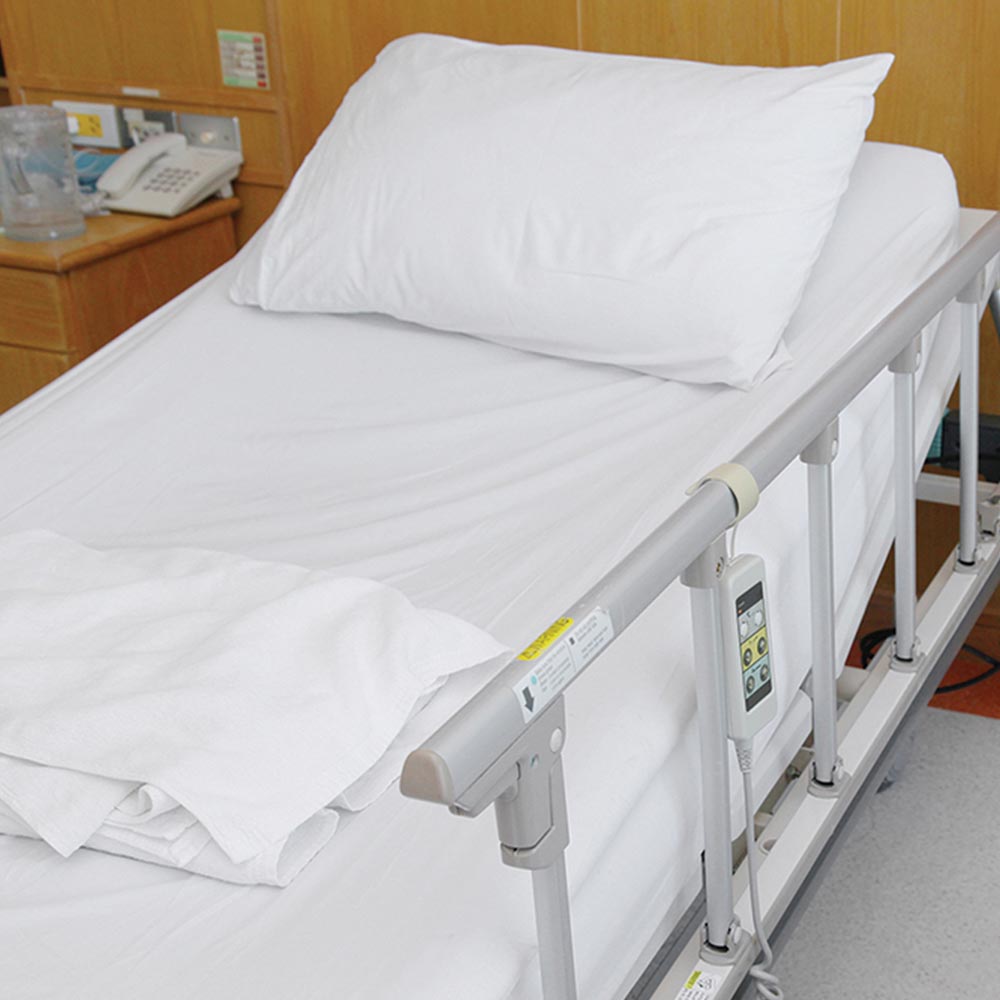 White pillow and bedsheet on a hospital bed with adjustable railing