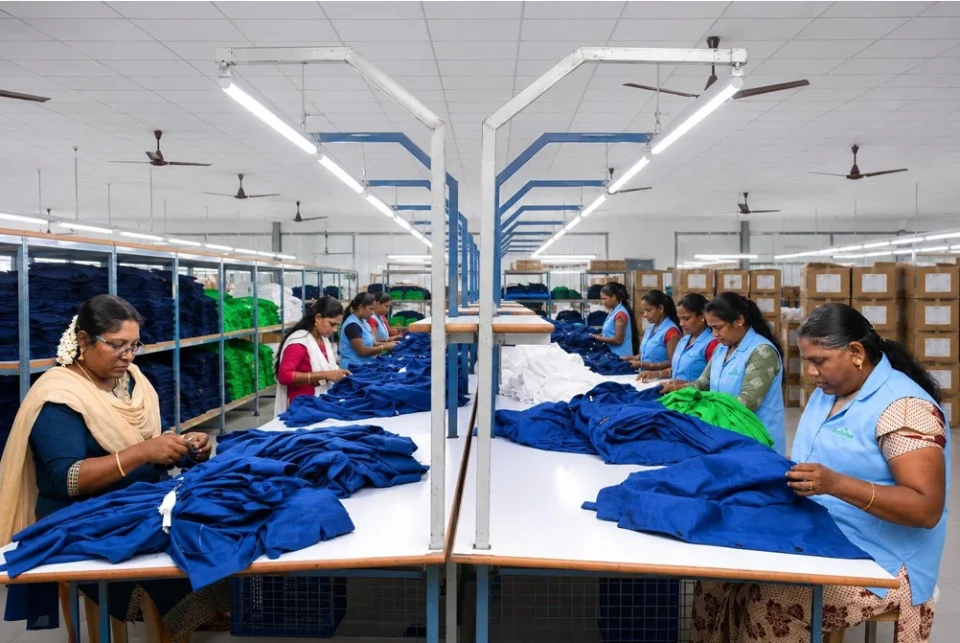Female textile factory workers stitching and quality checking blue garments at Reethatex manufacturing unit