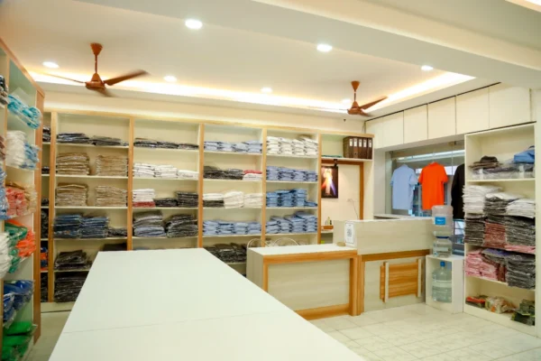 Bright interior view of Reethatex uniform showroom in Trivandrum with white display counter and stocked fabric shelves