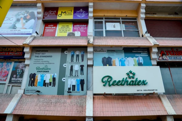 Exterior view of the multi-story Reethatex Uniforms store building showing brand signage and display posters in Trivandrum