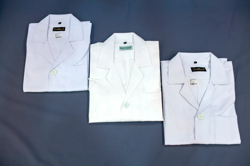 Folded white lab coats and doctor coats with brand collars by Reethatex Trivandrum