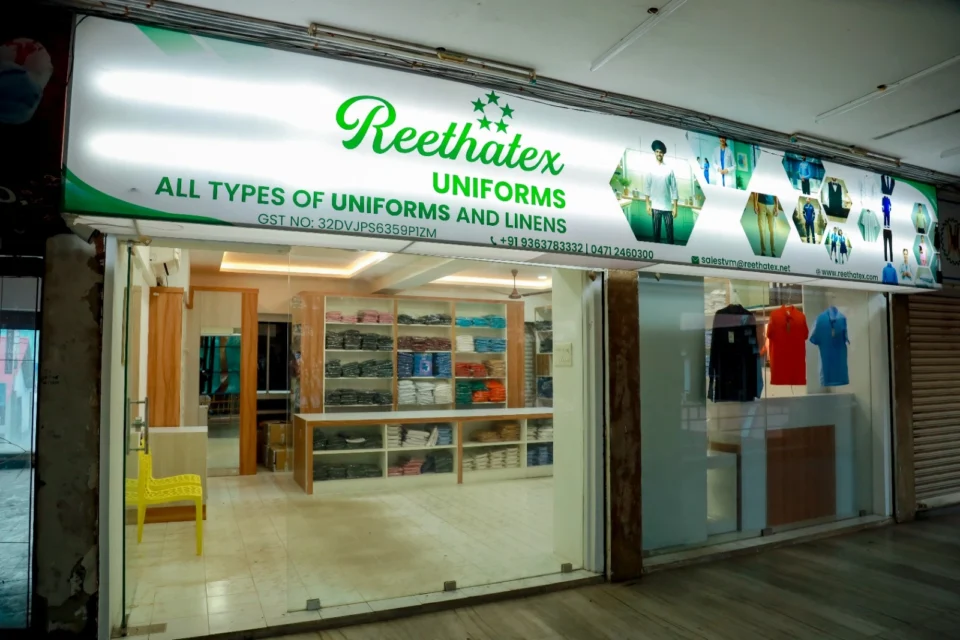 Reethatex Uniforms storefront with lighted brand signboard and glass entrance in Trivandrum
