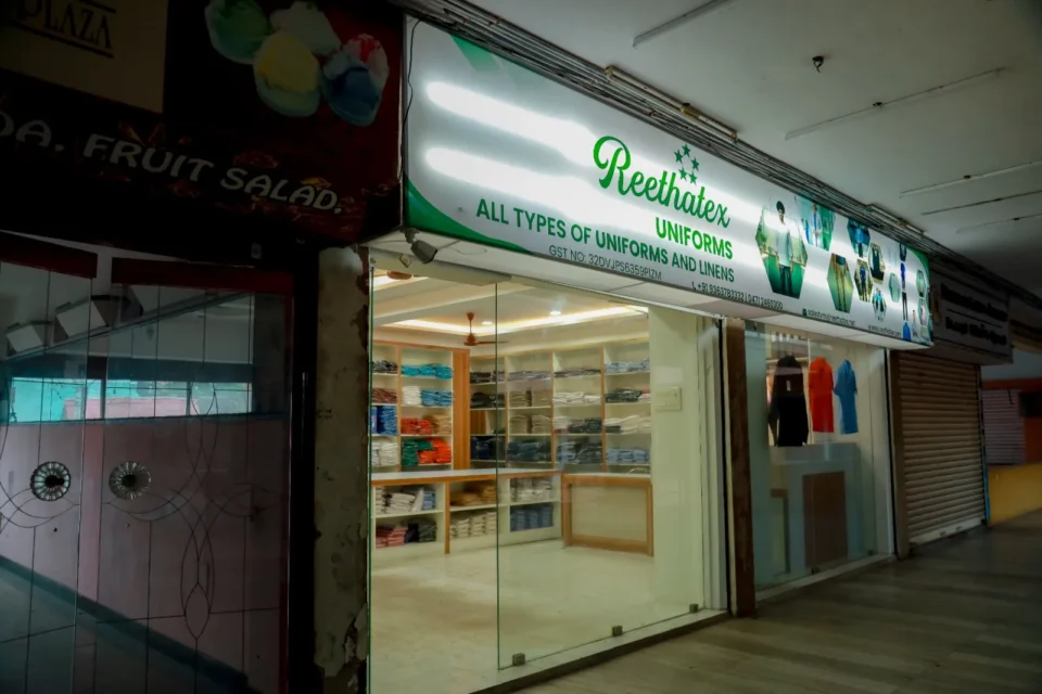 Reethatex Uniforms store front with green sign board and glass entrance display in Trivandrum